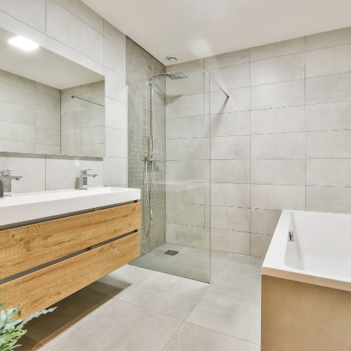 Modern bathroom with wooden vanity, shower, and bathtub.