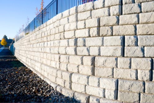 Stone retaining wall along a road with a clear blue sky.