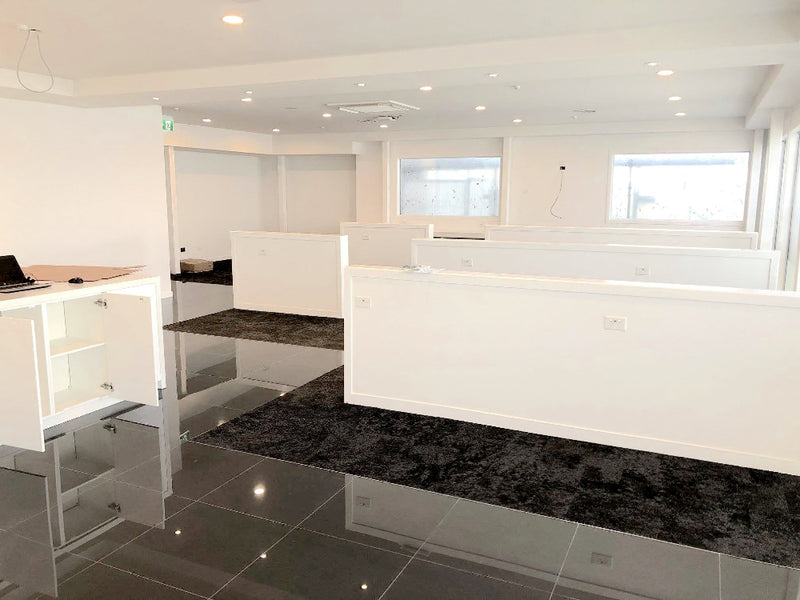 Modern office interior with white walls, black marble floor, and glass partitions.
