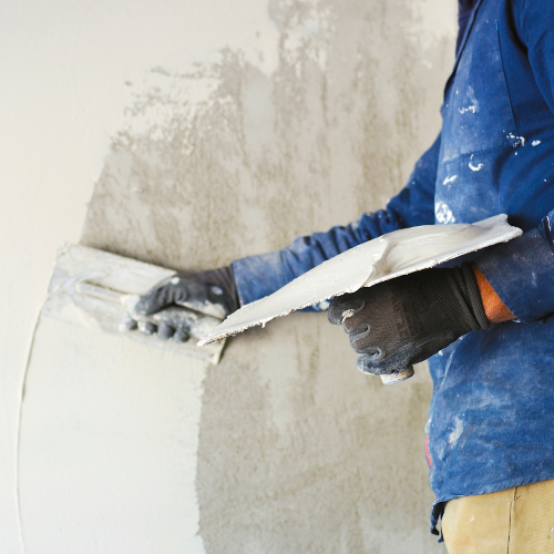 Person applying plaster to a wall with a trowel