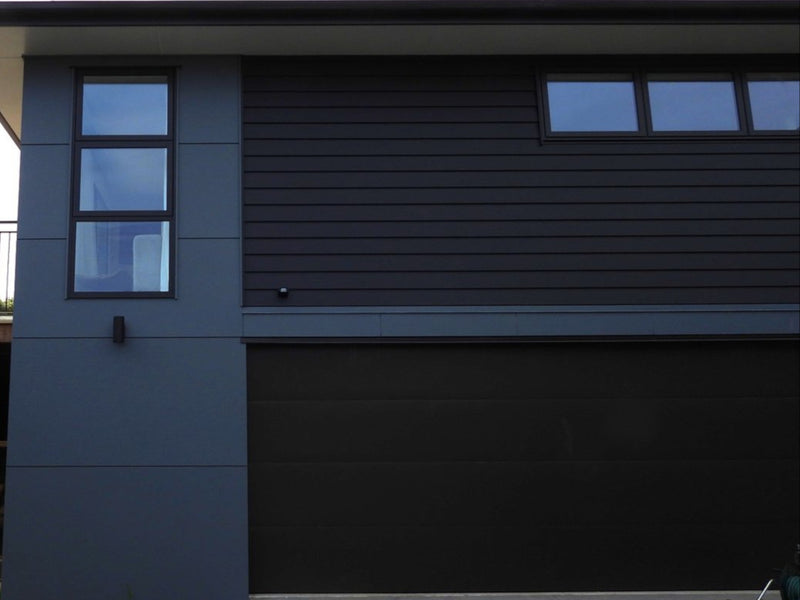 Modern house exterior with dark gray siding and a small deck.