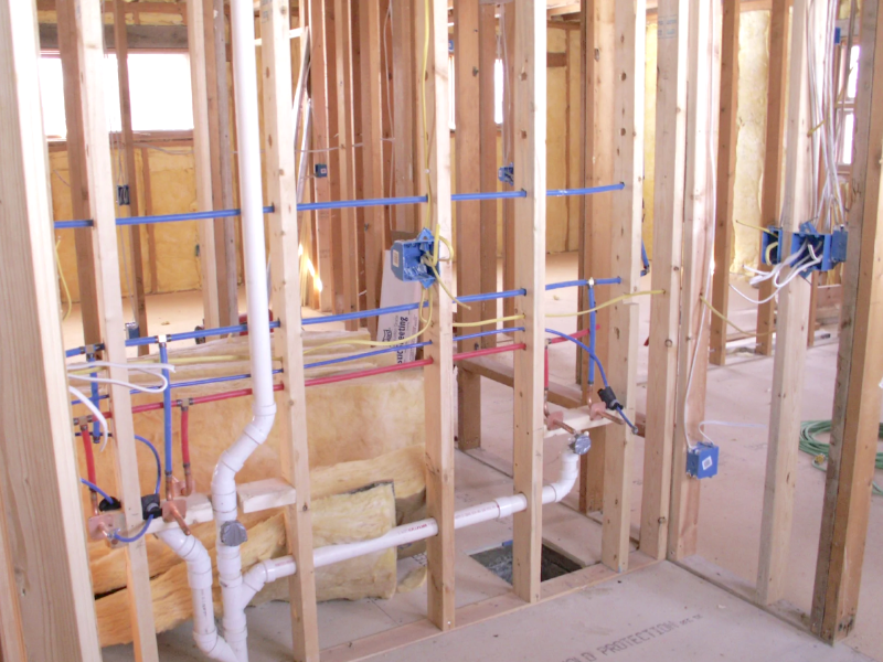 Under construction bathroom with exposed pipes and wooden framing