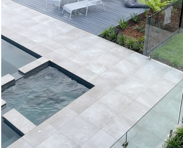 Small rectangular pool with tiled deck area in a backyard setting